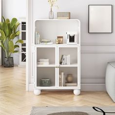 a white bookcase with glass doors and shelves in a room next to a couch