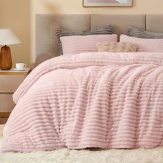 a bed with a pink comforter and pillows