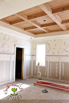 an empty room with unfinished walls and wooden ceiling beams in the process of being painted