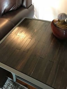 a brown leather couch sitting next to a wooden table with a vase on top of it