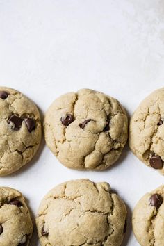 six chocolate chip cookies on a white surface