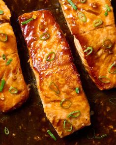 three pieces of meat with sauce and green onions on top in a skillet, ready to be cooked