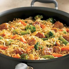 a skillet filled with noodles, meat and veggies on top of a table