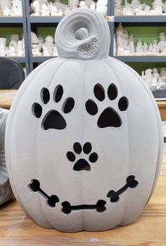 a large white pumpkin with paw prints on it's face and eyes, sitting on a table