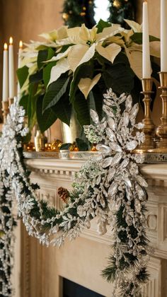 a fireplace mantel decorated for christmas with silver and white decorations, candles and poinsettis