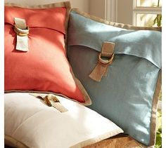 two pillows with tassels on them sitting next to each other