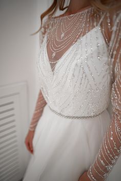 a woman in a white dress is standing near a radiator with her hands on her hips