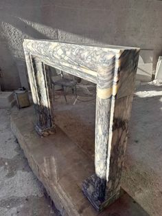 an old fireplace in the middle of a room with cement floors and walls around it