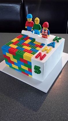 a cake made to look like legos on top of a white box with letters and numbers