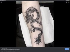 a black and white photo of a dragon tattoo on the arm