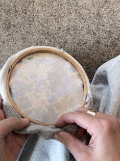 two hands are holding a round object with fabric on it and the other hand is stitching