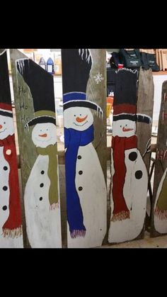 several snowmen painted on wooden boards with hats and scarves