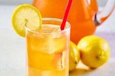 a pitcher and glass filled with lemonade next to some lemons