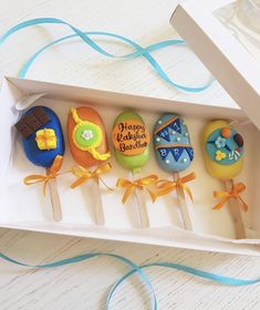 an open box with six decorated cookies in it