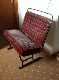 a red and black checkered bench sitting next to a white wall in a room