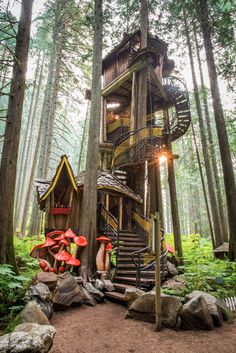 a tree house in the middle of a forest with stairs leading up to it's roof