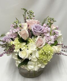 a vase filled with lots of white and purple flowers