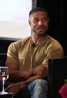 a man sitting in front of a screen with a glass of wine