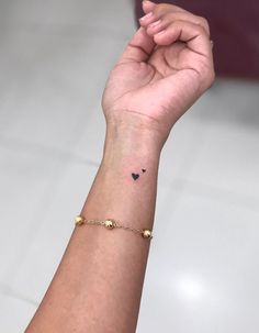 a woman's wrist with a small black heart tattoo on the left side of her arm