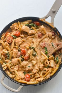 a skillet filled with pasta, chicken and tomatoes