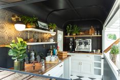 a kitchen with black and white walls, wooden counter tops and shelves filled with potted plants