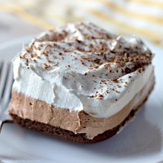 a piece of cake with whipped cream and chocolate shavings on top is sitting on a white plate