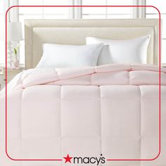 a pink comforter on a white bed in a room with windows and nightstands