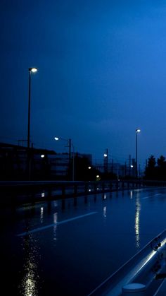 an empty parking lot at night with the lights on and water reflecting off the ground