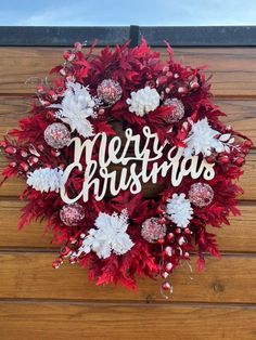 a christmas wreath with the words merry christmas written in white letters on top of it