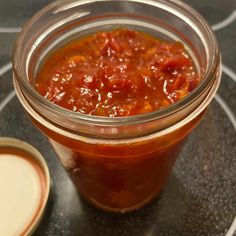 a glass jar filled with sauce sitting on top of a table