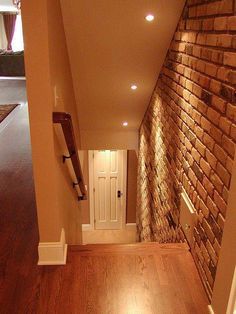 an empty room with wood flooring and brick wall in the corner, next to a white door