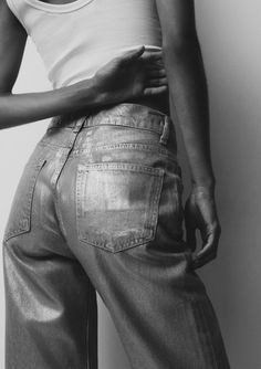 a black and white photo of a woman in high waist jeans with her hand on her hip