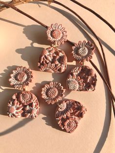 six pink flowers are sitting on top of a white surface next to some brown twigs