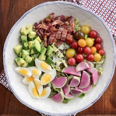 a white bowl filled with lots of different types of food on top of a wooden table