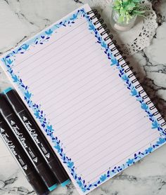 two pens sitting on top of a notepad next to a flowered notebook and pen