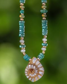 This stunning mother of pearl inlay shell necklace is truly one of a kind. This ammonite shell is inlaid with gorgeous mother of pearl for a piece you will find no where else since each shell is unique. It is paired with bright aqua blue apatite to bring in those Caribbean feels. There are accents in mother of pearl as well as fiery Ethiopian opals. It is truly a stunning piece that is elegant without being over the top. The perfect necklace for your summer escapades! Please note: Ethiopian opals are water absorbent. Please keep these away from water or excessive sweat. Do not shower, bathe, workout, or swim with these in order to keep these gems looking their fiery best. Your gems will thank you. Details: Mother of Pearl Ammonite Shell, Apatite, Ethiopian Opals, Mother of Pearl 14/20 Gold Unique Shell-shaped Mother Of Pearl Jewelry, Unique Mother Of Pearl Shell Jewelry, Unique Gemstone Necklace With Mother Of Pearl, Unique Mother Of Pearl Shell Pendant Necklace, Ocean-inspired Turquoise Shell Jewelry, Artisan Shell-shaped Mother Of Pearl Jewelry, Shell Shaped Gemstone Beads Jewelry For Gifts, Gemstone Beaded Shell Jewelry For Gifts, Artisan Mother Of Pearl Shell Jewelry