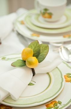 a table set with plates, silverware and lemons on top of each plate