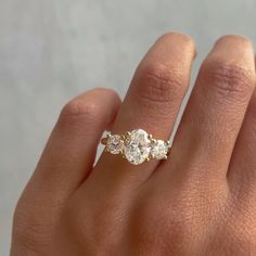 a woman's hand with a three stone ring on top of her left hand