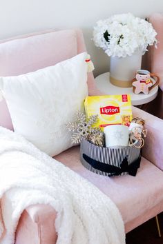 a pink chair sitting next to a white vase filled with flowers