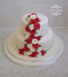 a three tiered white cake with red and white flowers