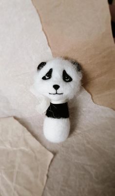 a small stuffed panda bear sitting on top of a piece of white paper with black eyes