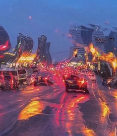 cars are driving down the road in heavy traffic on a rainy day, with buildings lit up behind them