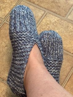 a person's feet wearing knitted slippers on a tile floor next to a tiled floor