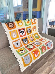 a crocheted blanket with animals on it sitting on a couch in a living room