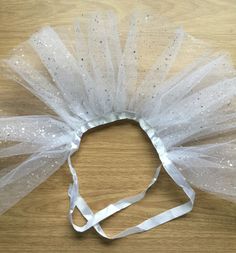 a white headband with silver sequins on it sitting on top of a wooden table