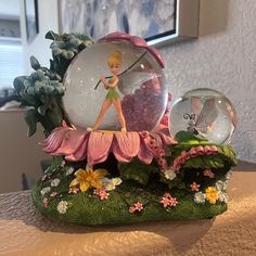 a snow globe with a tinkerbell figurine in it on a table