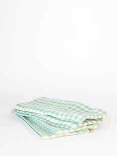 three green and white towels folded on top of each other in front of a white background