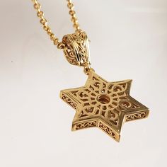 Elevate your personal style with our exquisite Gold-Plated Star of David Pendant, a symbol of faith and cultural significance. This pendant beautifully captures the essence of the Star of David, adorned with a captivating garnet or stone at its center, adding a touch of elegance and meaning to your jewelry collection. Measuring a graceful 1.8 inches (45 mm) in length and 0.8 inches (20 mm) in width, this pendant boasts intricate craftsmanship that showcases the star's delicate interlocking trian Elegant Star Of David Hallmarked Necklace, Gold Star Of David Gemstone Jewelry, Gold Star Of David Jewelry With Gemstone, Elegant Star Of David Gemstone Necklace, Elegant Birthstone Necklace With Star Of David, Elegant Star Of David Birthstone Jewelry, Star Of David Meaning, The Star Of David, Star Of David Necklace