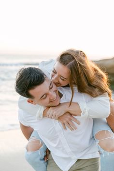 a man and woman hug each other on the beach