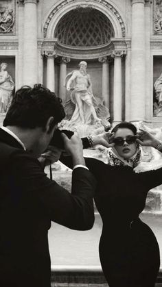 a man and woman standing in front of a fountain